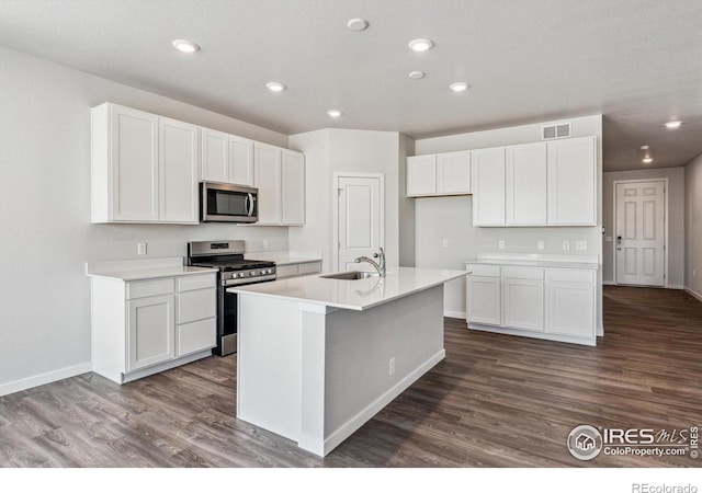 kitchen with sink, white cabinetry, stainless steel appliances, dark hardwood / wood-style floors, and a center island with sink