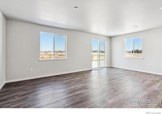 unfurnished room with dark wood-type flooring and a textured ceiling