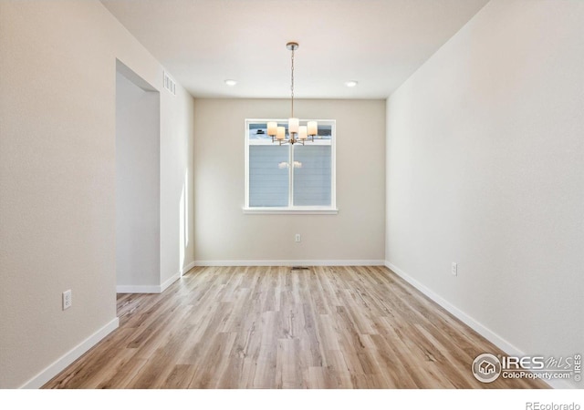 unfurnished dining area with a chandelier and light wood-type flooring