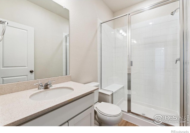 bathroom with vanity, a shower with shower door, and toilet