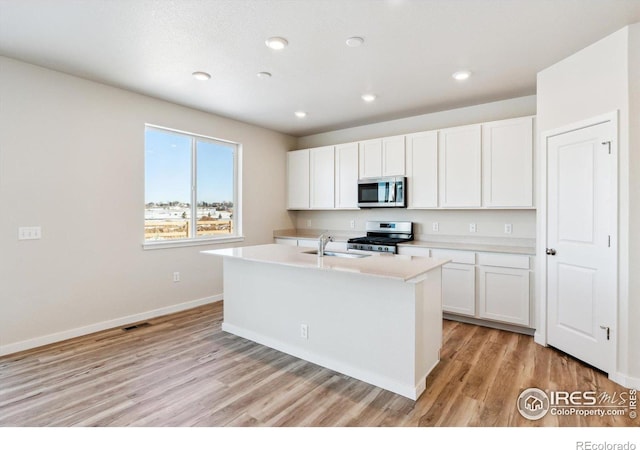 kitchen with sink, white cabinetry, light wood-type flooring, an island with sink, and stainless steel appliances