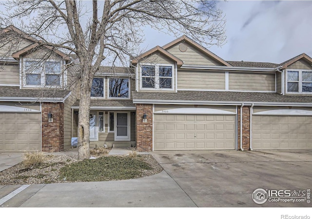 townhome / multi-family property featuring a garage, concrete driveway, and brick siding