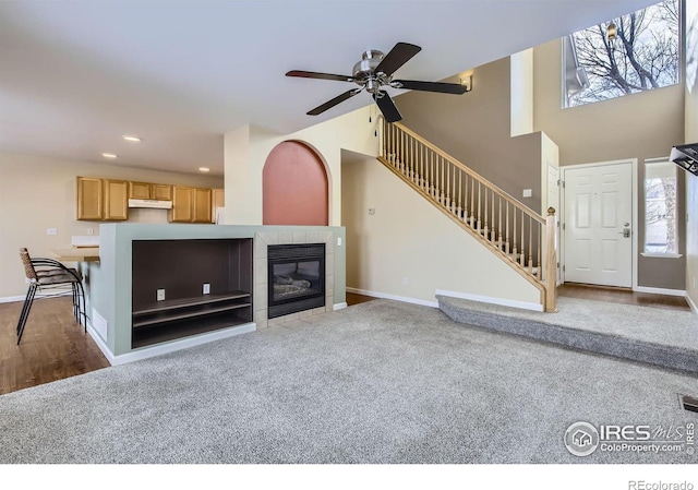 unfurnished living room featuring baseboards, a tile fireplace, stairway, and recessed lighting