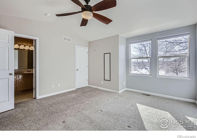 unfurnished bedroom featuring visible vents, carpet flooring, vaulted ceiling, a sink, and baseboards