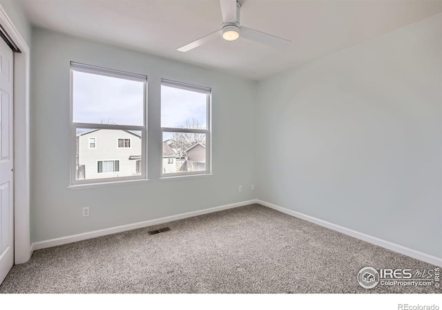 carpeted empty room with visible vents, ceiling fan, and baseboards