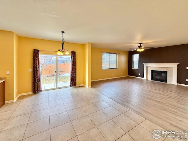 unfurnished living room featuring a tile fireplace, light hardwood / wood-style floors, and ceiling fan