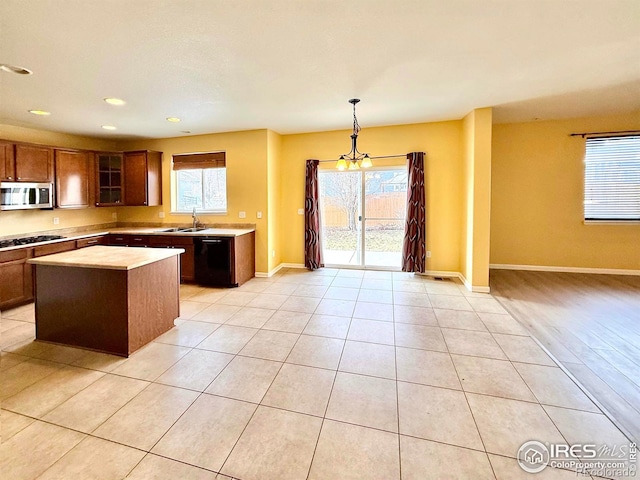 kitchen with light tile patterned flooring, appliances with stainless steel finishes, sink, hanging light fixtures, and a center island