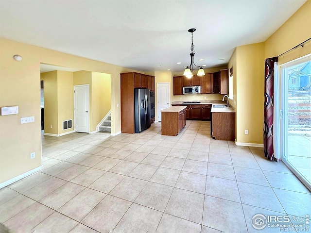 kitchen featuring black fridge with ice dispenser, sink, decorative light fixtures, light tile patterned floors, and a kitchen island