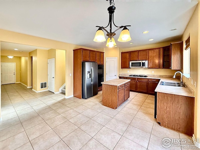 kitchen with pendant lighting, sink, light tile patterned floors, a center island, and black appliances