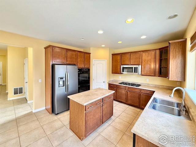 kitchen with sink, light tile patterned floors, a center island, and appliances with stainless steel finishes