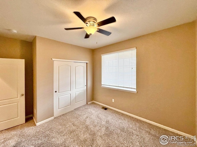 unfurnished bedroom with carpet floors, ceiling fan, and a closet