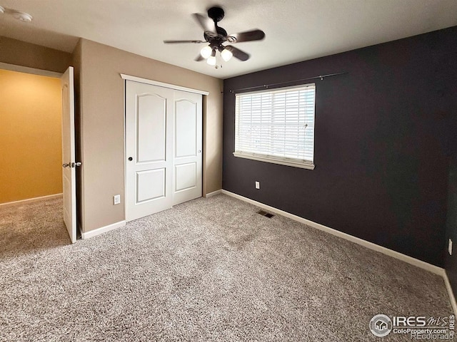 unfurnished bedroom with ceiling fan, carpet flooring, and a closet