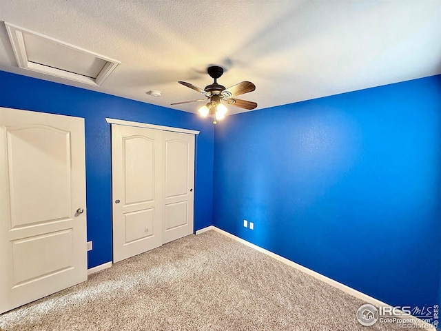 unfurnished bedroom with ceiling fan, light carpet, a textured ceiling, and a closet