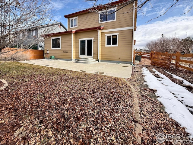 snow covered rear of property with cooling unit and a patio area