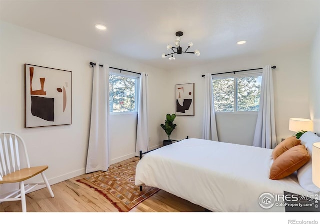 bedroom with a notable chandelier and light wood-type flooring