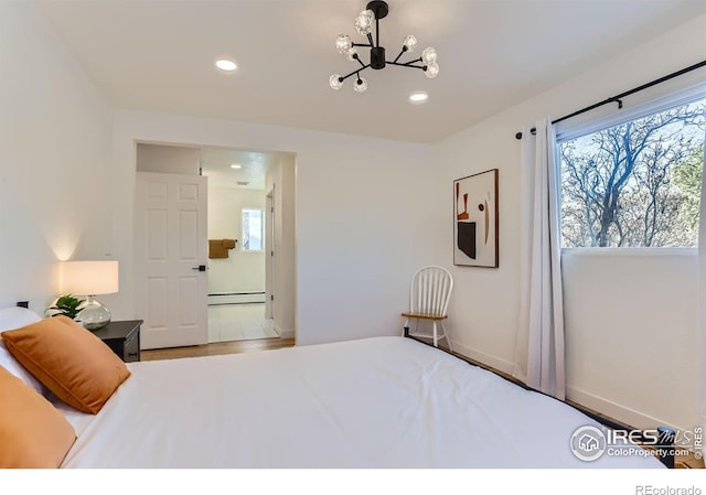 bedroom featuring a notable chandelier, wood-type flooring, and a baseboard heating unit