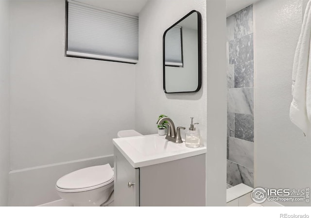 bathroom featuring vanity, toilet, and a tile shower