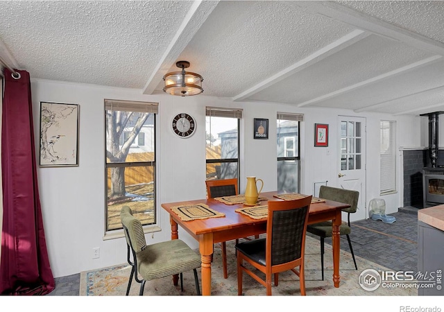 dining area featuring beamed ceiling, carpet, a wood stove, and a textured ceiling