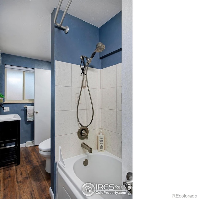 full bathroom featuring tiled shower / bath, wood-type flooring, vanity, and toilet