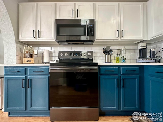 kitchen featuring blue cabinets, tasteful backsplash, light wood-type flooring, appliances with stainless steel finishes, and white cabinets