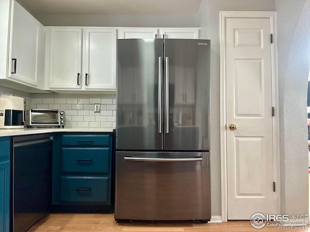 kitchen featuring blue cabinetry, light hardwood / wood-style flooring, stainless steel refrigerator, decorative backsplash, and white cabinets