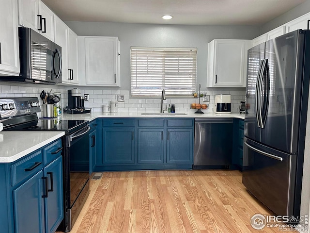 kitchen featuring appliances with stainless steel finishes, sink, white cabinets, blue cabinetry, and light hardwood / wood-style flooring