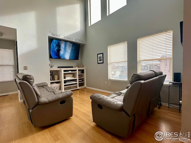 living room with a towering ceiling and light wood-type flooring