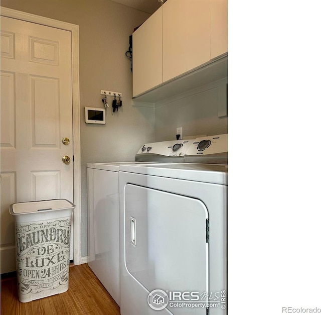 washroom with separate washer and dryer, light hardwood / wood-style flooring, and cabinets