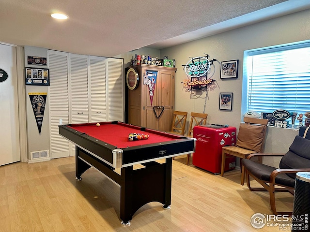 game room with a textured ceiling, light hardwood / wood-style floors, and billiards