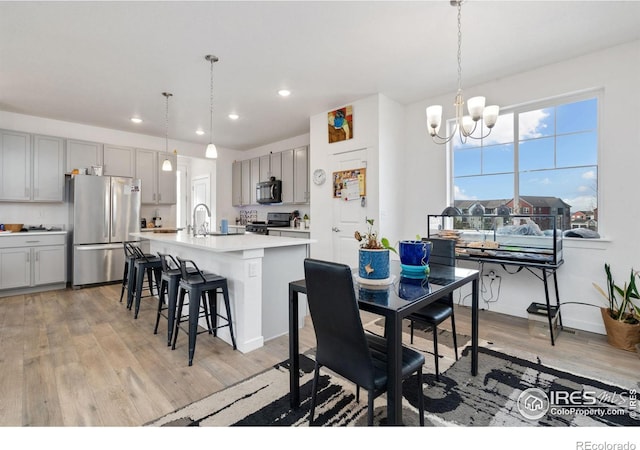 dining room featuring sink, light hardwood / wood-style flooring, and a notable chandelier