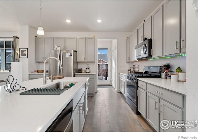 kitchen featuring decorative light fixtures, sink, gray cabinetry, hardwood / wood-style flooring, and stainless steel appliances