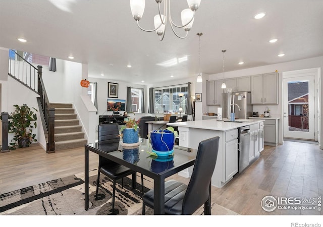 dining room featuring sink, a notable chandelier, and light hardwood / wood-style floors