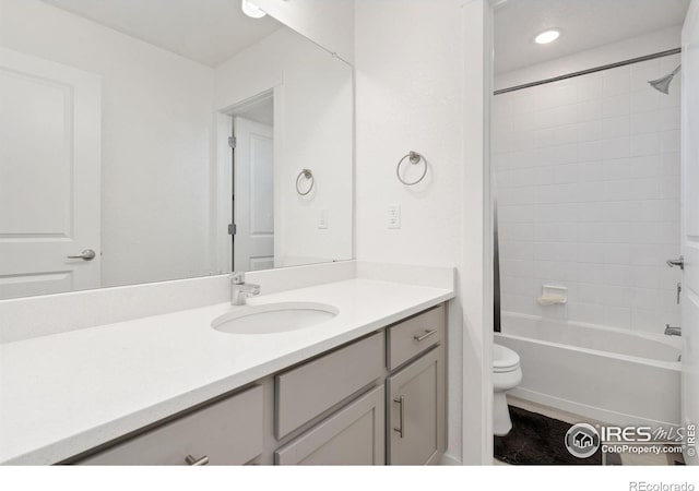 full bathroom featuring vanity, tiled shower / bath combo, and toilet