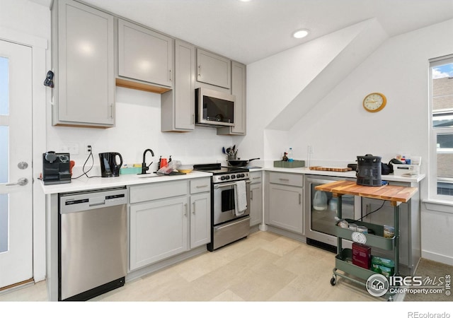 kitchen featuring stainless steel appliances, sink, and gray cabinetry