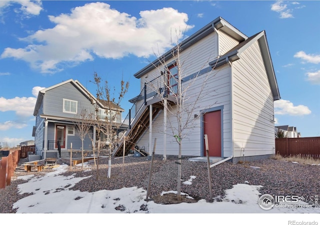 snow covered rear of property with a balcony