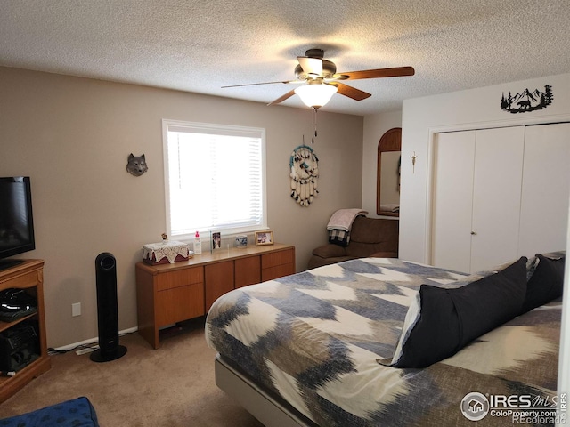 bedroom with ceiling fan, light colored carpet, a textured ceiling, and a closet