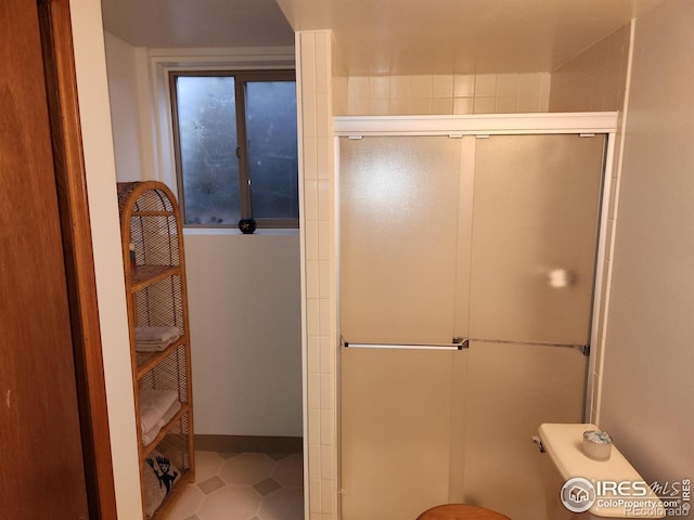 bathroom featuring a shower with door and toilet