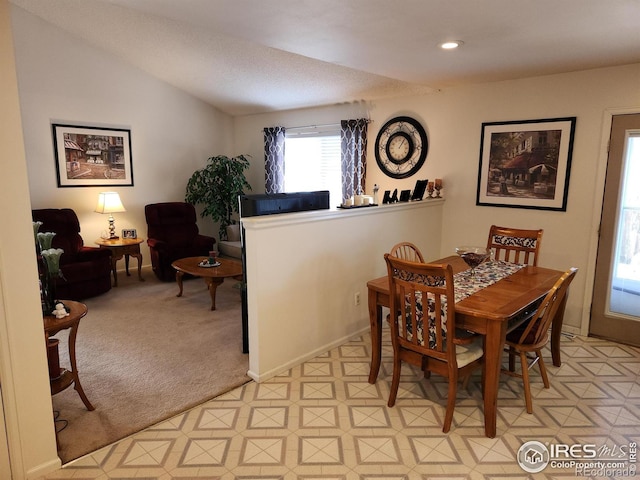 carpeted dining space with lofted ceiling