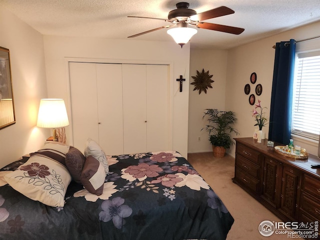 carpeted bedroom with ceiling fan, a closet, and a textured ceiling