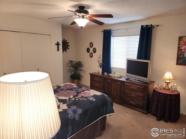 carpeted bedroom featuring ceiling fan, a closet, and a textured ceiling