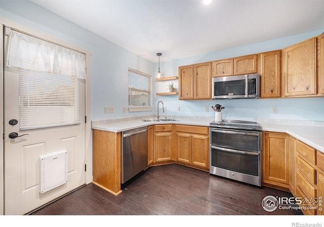 kitchen with dark wood-type flooring, stainless steel appliances, sink, and hanging light fixtures