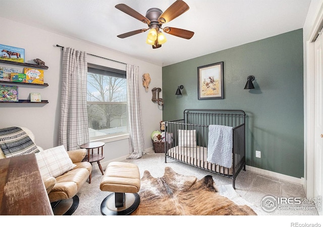 bedroom featuring light carpet, a crib, and ceiling fan