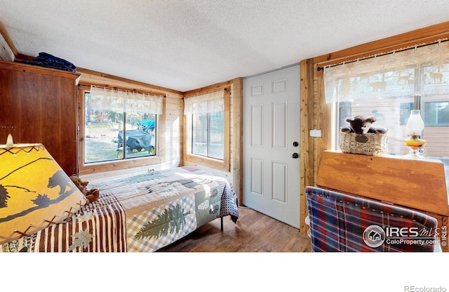 2420 Big Owl Rd, Allenspark, CO 80510 - bedroom featuring wooden walls, hardwood / wood-style floors, and a textured ceiling