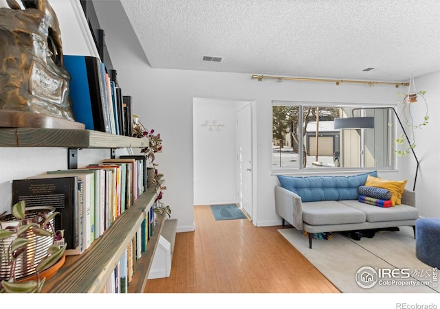 living room featuring light hardwood / wood-style flooring and a textured ceiling