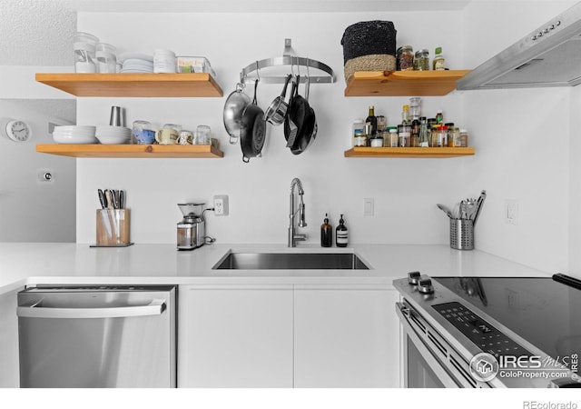 interior space with white cabinetry, stainless steel appliances, sink, and wall chimney range hood