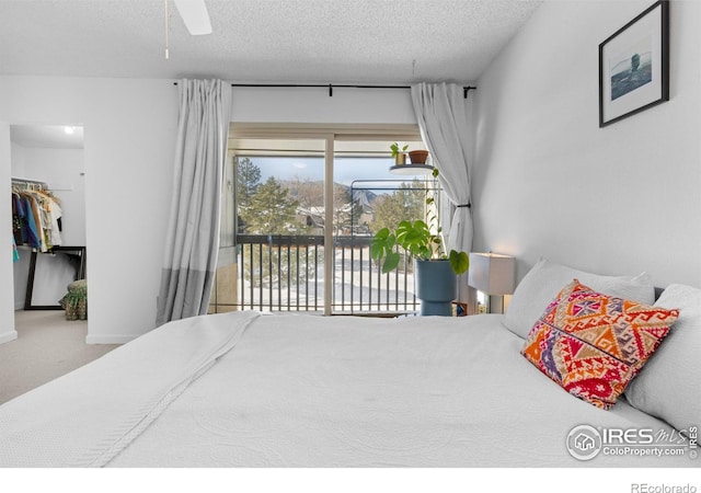 bedroom with a walk in closet, access to exterior, carpet floors, and a textured ceiling