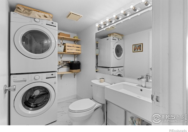 bathroom with stacked washer and clothes dryer, toilet, and vanity