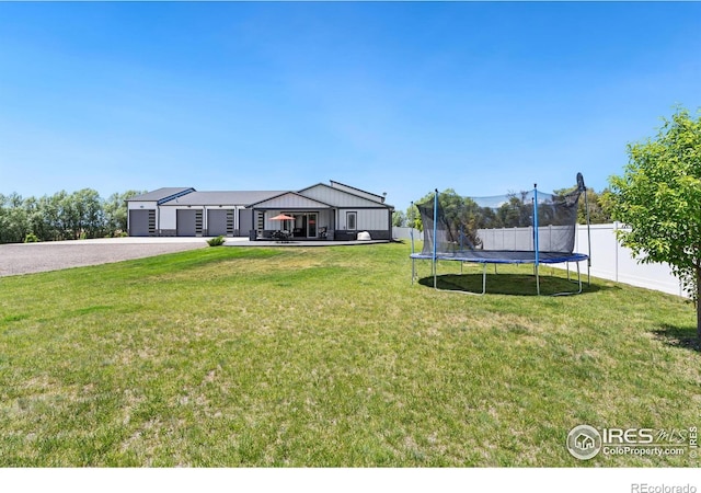 view of yard with a garage and a trampoline