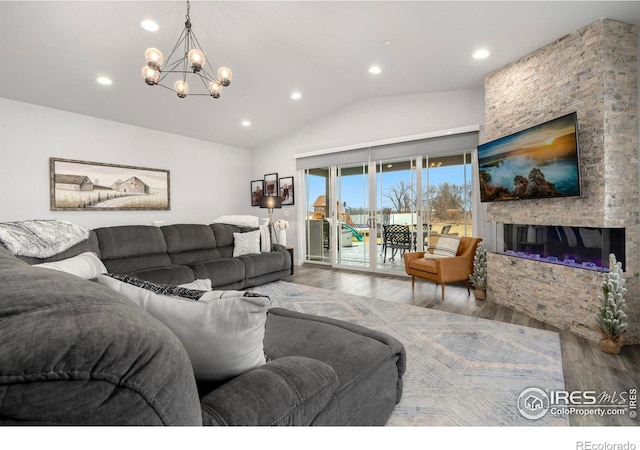 living room featuring wood-type flooring, a fireplace, a chandelier, and vaulted ceiling