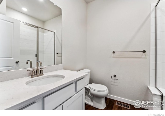 bathroom featuring vanity, toilet, an enclosed shower, and hardwood / wood-style floors